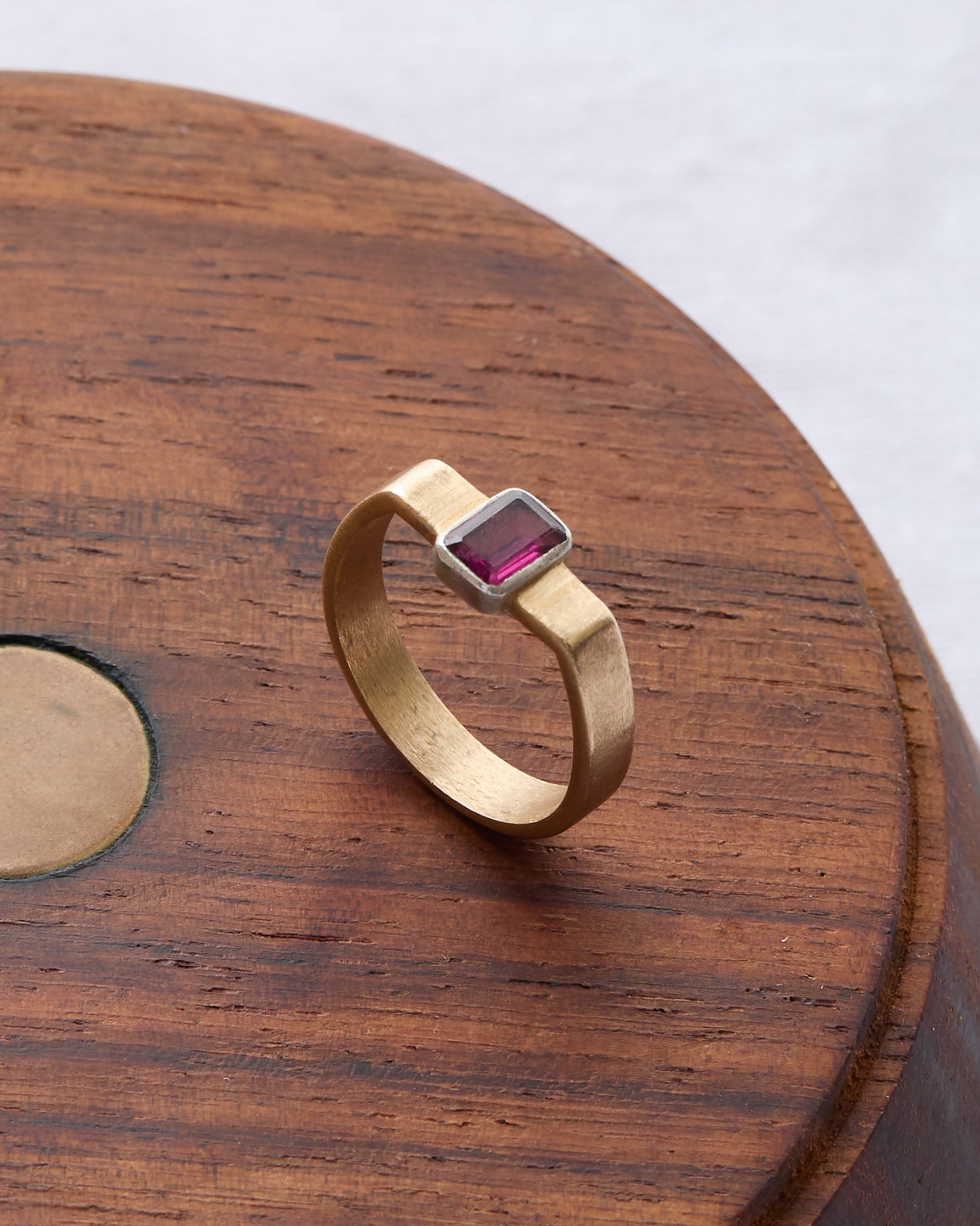Gold cuff ring featuring a deep pink rhodolite gemstone at its center