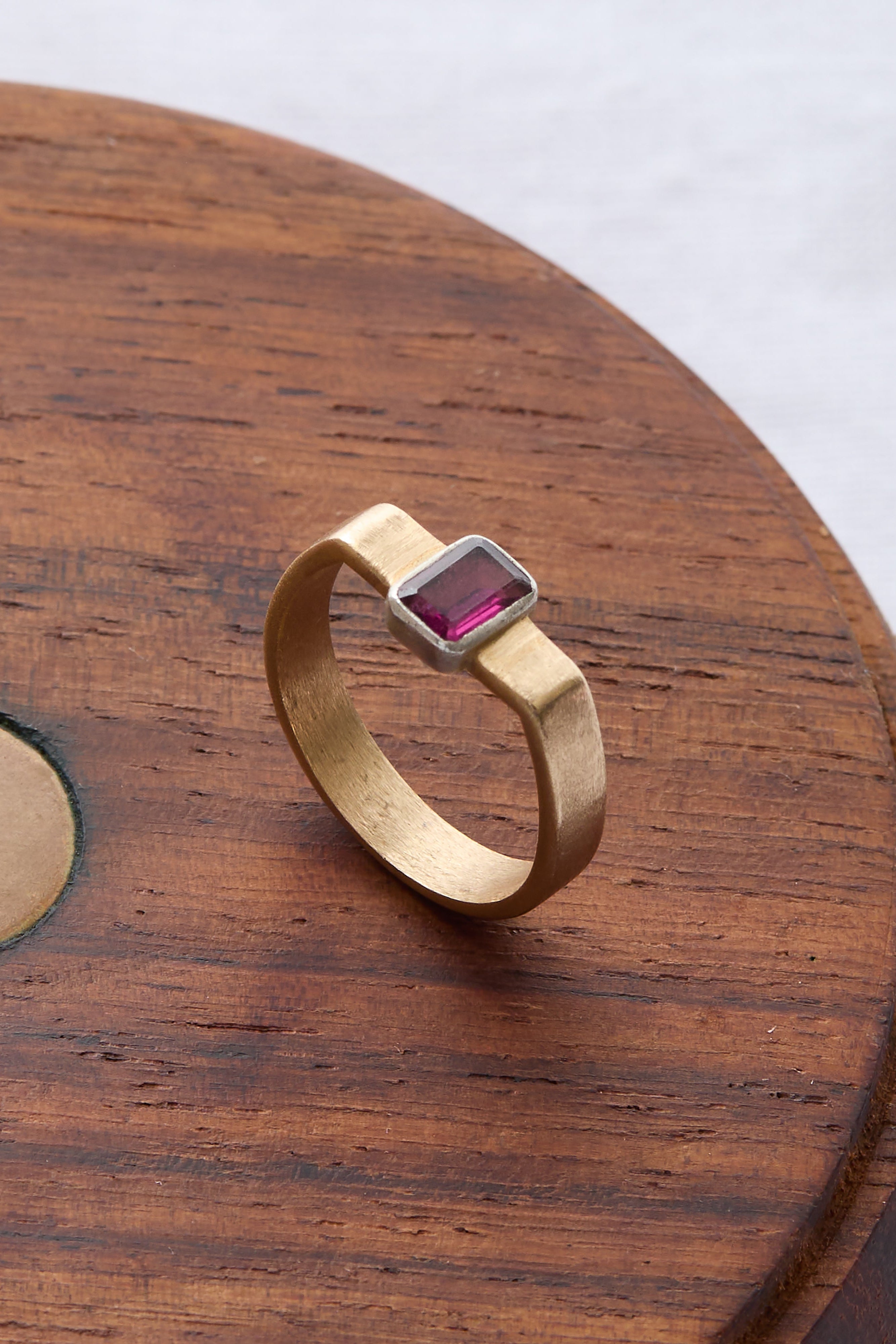 Gold cuff ring featuring a deep pink rhodolite gemstone at its center