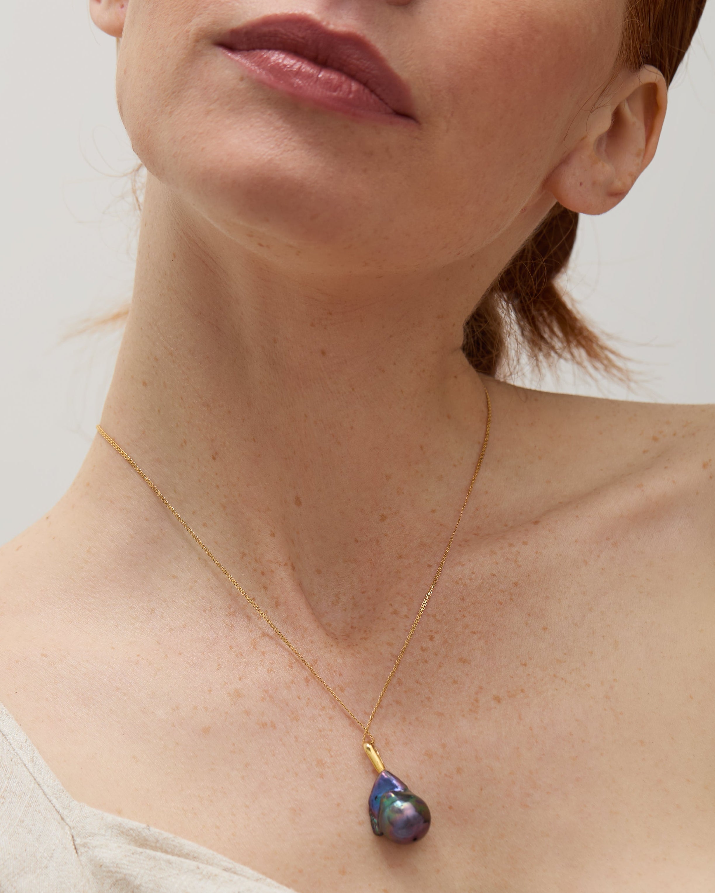 Model wearing the baroque pearl pendant, showcasing its elegant drop design.